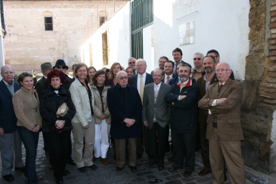 Asistentes junto al muro en el que puede verse la placa conmemorativa